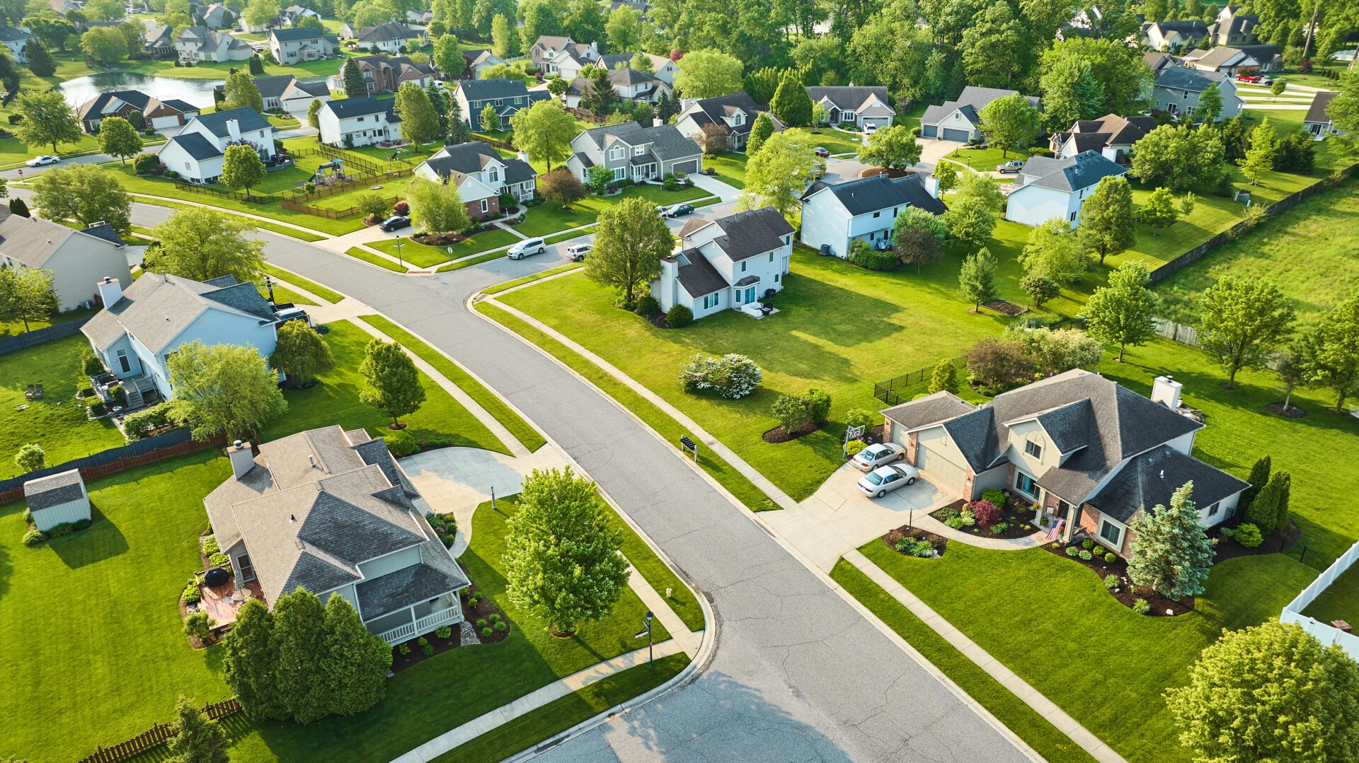 Illustrative aerial stock photograph of spacious lawns, mature trees, and detached homes