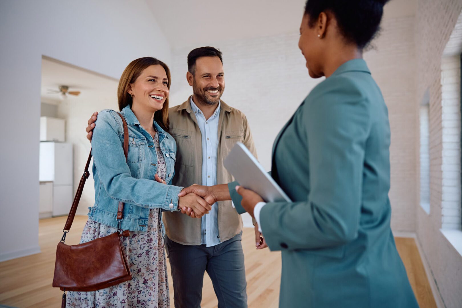 It's a deal, we are buying this house! Couple meeting real estate agent in house.