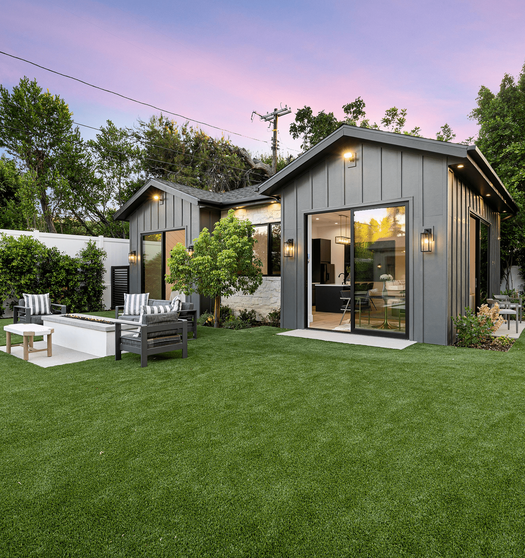 Stock photograph of a landscaped lawn, outdoor seating, and a contemporary home at dusk