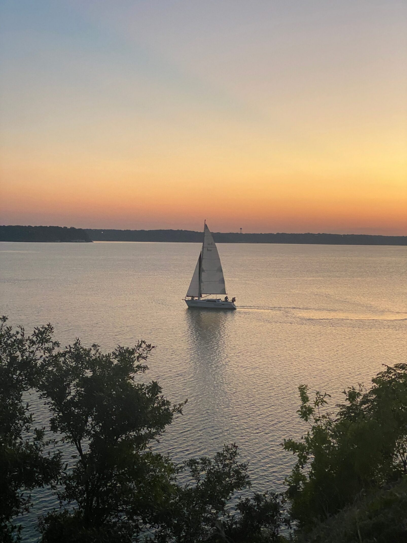 Sailboat at sunset on a Texas lake, illustrating a lakeside lifestyle